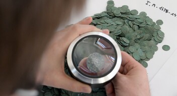 Nagy Balázs régész vizsgál egy I. Mátyás korabeli ezüst denárt az újlengyeli éremleletből-3